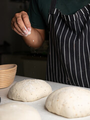 Baker Sprinkling Flour on Sourdough Dough - Artisan Breadmaking Process