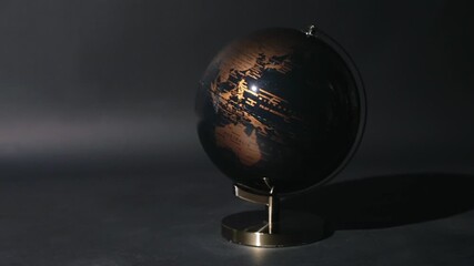 Rotating black and gold antique style globe on dark isolated studio background - Powered by Adobe