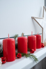 Four Advent red candles, fir branches and Christmas zero waste decorations in windowsill. Holiday preparation copy space for text. Catholic traditions of Christmas new year winter holidays 