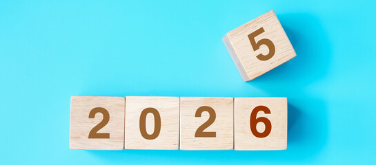 wooden cube block with 2026 text on blue background. Resolution, plan, review, goal, start and New Year holiday concepts