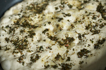 Close-up of raw pie with herbs. Focaccia making process.