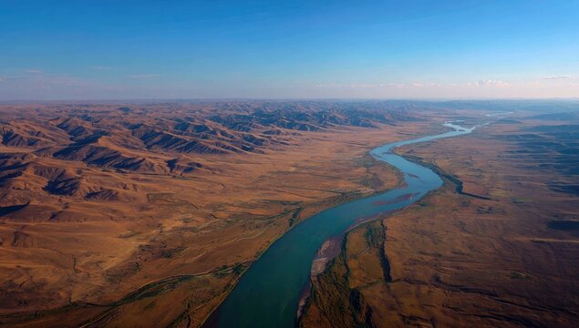 High-angle view of a river winding through a dry, mountainous landscape - Powered by Adobe