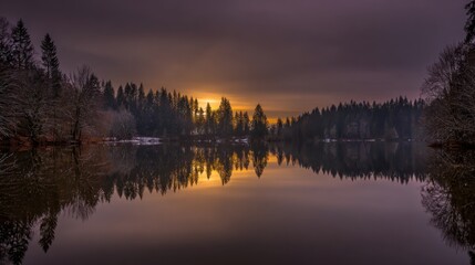 Fototapeta premium A serene lake mirroring golden sunset and forest, creating a perfectly symmetrical dreamscape.