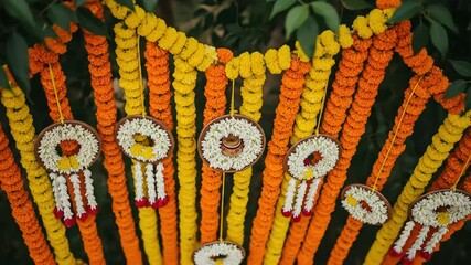 Bright Indian Wedding Garland Decoration in Yellow Orange and White Traditional Floral String Ornaments Hanging From Foliage for Celebration Backdrop
