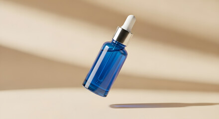 Blue glass bottle with dropper for serum or essential oil on beige background