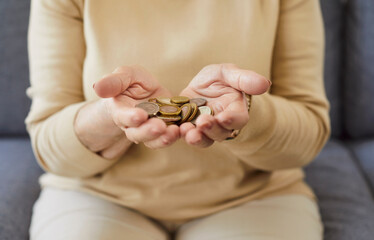 Close-up of senior woman hands holding coins, managing finance and money cash for savings, pension wealth or poverty, focus on economic challenges or careful budgeting in a modest lifestyle.
