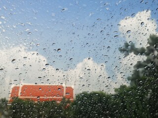 Rain drops on the window . Windshield on rainy days, visible outside the building.
(This orange roofed building is a place for monks called a temple in Buddhism.)