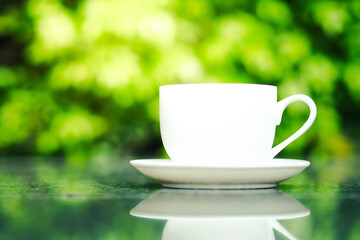 Coffee cup on the table and green nature background