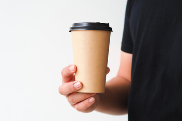 Young man hand holding coffee paper cup on white background. Mockup for you designs.