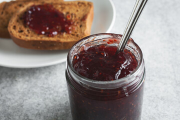 A closeup view of a jar of raspberry preserves.