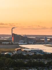 Aerial view of Copenhagen, Denmark, at sunset with Amager Bakke waste to energy plant, green spaces, residential areas, and urban structures visible.