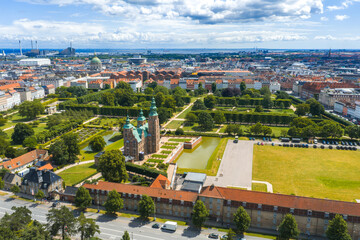 Aerial view of Rosenborg Castle, King's Garden, and Copenhagen's cityscape with red roofed buildings, Frederik's Church, and a waste to energy plant.