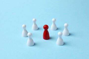 One red pawn among white ones on table. Difference and uniqueness concept