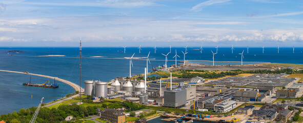 Aerial view of Copenhagen, Denmark, featuring a waste to energy plant, silos, wind turbines at sea, a harbor, and modern and traditional buildings.