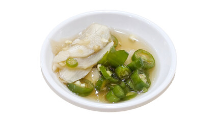 Small white bowl containing sliced green chili peppers and garlic in fish sauce, a popular Thai condiment, isolated on white background