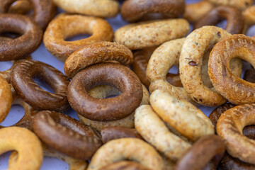 Freshly baked mini bagels on a dark background. Top view. Pretzels in the form of a ring close-up. Small bread circle biscuit. Bowls with different types of bagels.