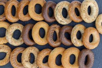 Freshly baked mini bagels on a dark background. Top view. Pretzels in the form of a ring close-up. Small bread circle biscuit. Bowls with different types of bagels.