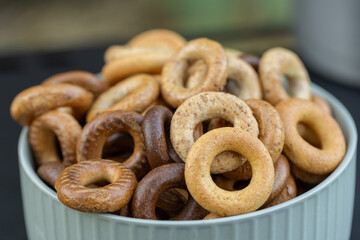 Freshly baked mini bagels on a dark background. Top view. Pretzels in the form of a ring close-up. Small bread circle biscuit. Bowls with different types of bagels.