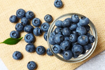 Ripe blueberries in a wooden bowl on a background of scattered berries. Healthy and dietary nutrition concept. Top view.