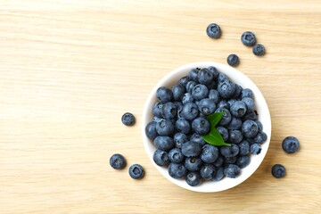 Top view of bowl with fresh tasty blueberries on wooden  table, close up