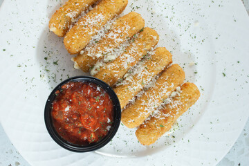 A top down view of a plate of mozzarella sticks.