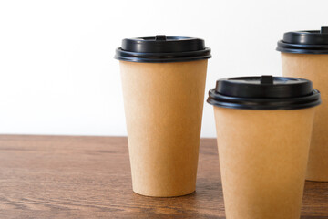 Coffee paper cup on wooden table. Mockup for you designs.