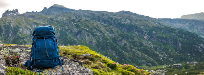 Hiking backpack on rock during trekking in mountains. Hike and travel outdoor equipment. Panoramic...
