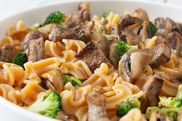 A closeup view of a steak pasta entree, featuring gluten-free cascatelli pasta.