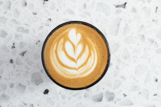 A top down view of a latte coffee drink, featuring latte art.