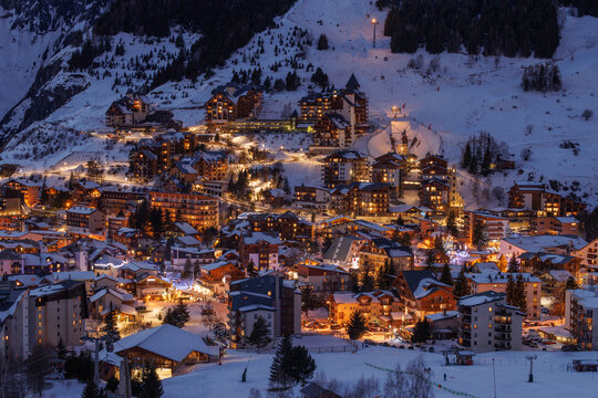 Snowy alpine village glows with warm golden lights at twilight