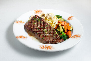 A view of a plate of steak and pasta.