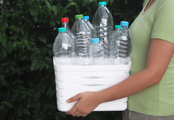 Woman hand holding bucket with plastic bottles for recycle. Plastic recycle concept.