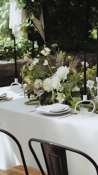 Wedding table decor in a restaurant. Beautiful and elegant floral table setting with candles on a fresh green background.