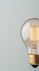 Incandescent light bulb glowing with warm light, close up on a neutral background, concept for ideas and innovation.