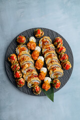 Tempura sushi roll on a black plate on a light background