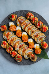 Tempura sushi roll on a black plate on a light background