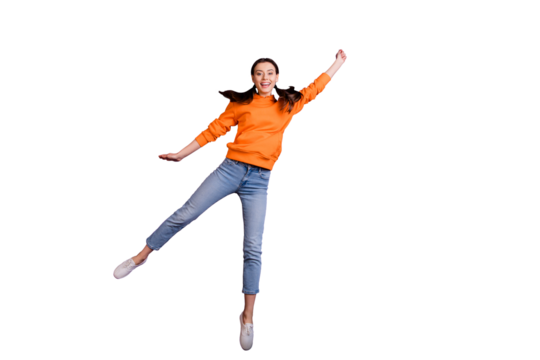 Full size photo of positive cheerful teen girl hold hand jump catch her flying parasol on windy weather wear orange sporty outfit jeans white sneakers isolated over violet purple color background