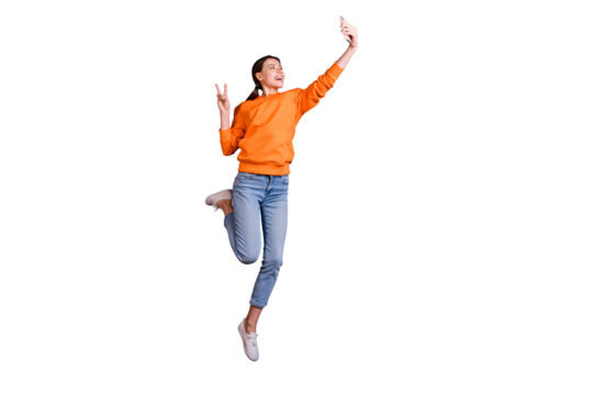 Full length photo of positive cheerful youth teen girl with  ponytails have trip journey take selfie make v-signs wear orange sportive wear jeans sneakers isolated violet purple color background - Powered by Adobe