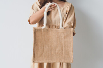 Woman holding  jute bag or sack bag on white background. Reusable shopping bag. Natural material. Zero waste. Plastic free. Eco friendly concept.