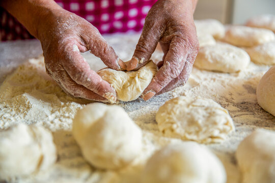 Homemade cakes dough in the women's hands. Process of making pies, hand. Cooks dough for baking, pieces of raw dough. Womans hands rolling doughs for pies. Baking at home.