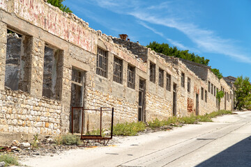 Abandoned stone buildings along a quiet road in Croatia on a sunny day