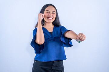 Fototapeta premium A cheerful young woman smiling brightly with eyes closed, celebrating success with a confident fist pump.