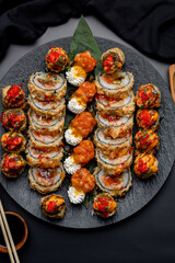 Tempura sushi roll on a black plate on a black background