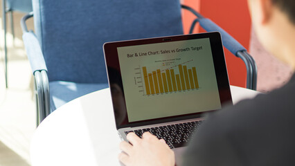Person analyzing bar and line chart on laptop showing sales versus growth target in a business...