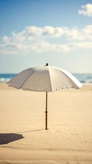 White beach umbrella on sandy shore under a partly cloudy sky