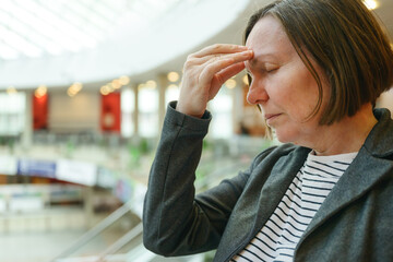 Troubled businesswoman with headache in bright corporate office building interior