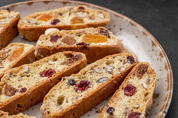 Italian Almond Biscotti biscuits in a rustic home made pottery bowl. Studded with almonds and cranberries, these twice-baked treats are aromatic and inviting. Ideal.