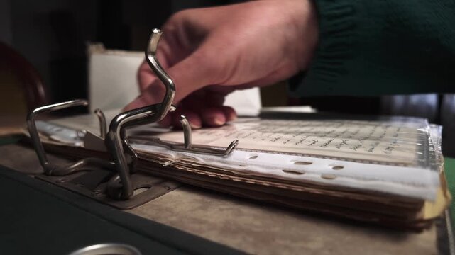 Home archivist organising personal documents into A4 protective sleeve