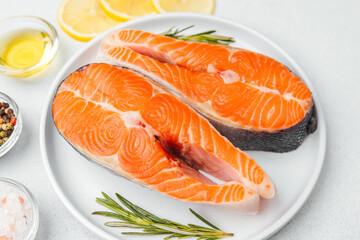 Fresh salmon fillets prepared for cooking with lemon and herbs on a plate
