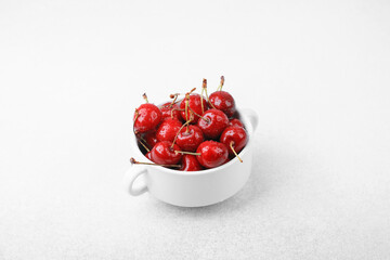Close‑up cherries in white cup on white for macro fruit texture or premium ingredient concept